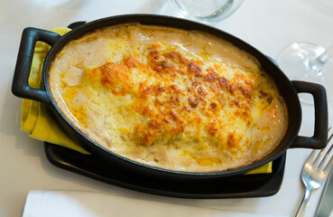 Traditional Spanish meat lasagna with parmesan cheese served in iron pan