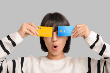 Beautiful young woman with credit cards on grey background