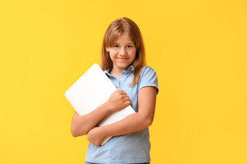 Portrait of teenage girl with laptop on yellow background