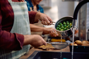 Close up of man preparing brussels sprouts in  kitchen.