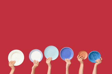 Hands holding empty plates on red background