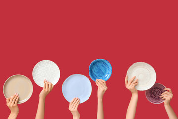 Hands holding empty plates on red background