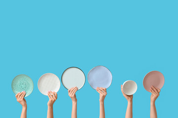 Hands holding empty plates on blue background