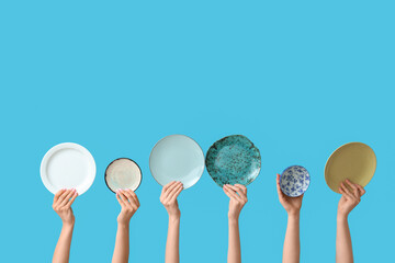 Hands holding empty plates on blue background