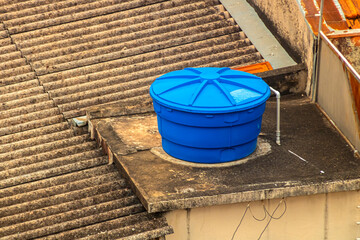 Blue water tank installed on top of a building or residence, in a concrete structure. Reservoir used for storing water.