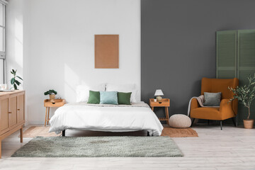 Beautiful bedroom with brown armchair, bedside table, olive tree and soft bed