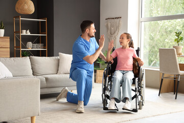Little girl in wheelchair with nurse giving each other high-five at home
