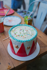 Beautiful creamy circus birthday cake close up still on a wooden table 