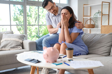 Young man calming down his upset wife at home. Bankruptcy concept