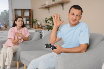 Obraz premium Young man playing video game and his quarreling wife at home
