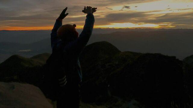 Silueta de mujer levantando los brazos en la cima de las monta&ntilde;as, amanecer en alto contraste