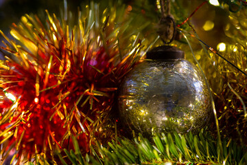 Silver festive bauble with cracked mirror effect on Christmas tree with gold and red tinsel.