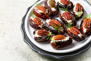 Stuffed Dates with goat cheese, mayonnaise, pecan nuts. Festive appetizers, White table surface.