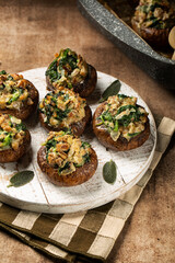 Vertical image of Baked Cremini Mushrooms stuffed with roasted mushrooms legs, with onion, spinach, bread crumbs and goat cheese.