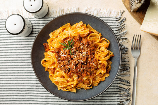 Top view of plate with Tagliatelle al ragu  - long, flat egg pasta with a meat sauce or Bolognese sauce and parmesan cheese, served with rosemary.