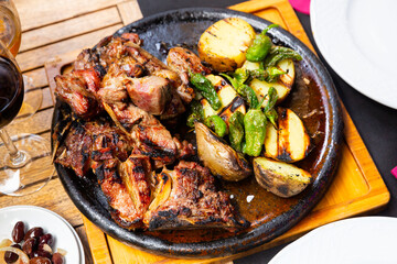 Pieces of appetizing roasted veal chop with side dish of baked potatoes and jalapenos pepper