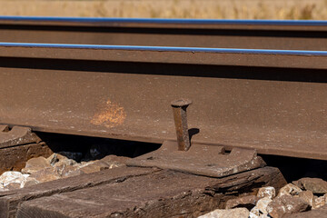 Railroad tracks with spike sticking up. Railway maintenance, track repair and transportation infrastructure safety concept.