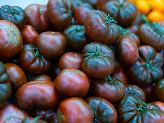 Ripe tomatoes of the Negros variety, put up for sale on the supermarket counter. Close-up image