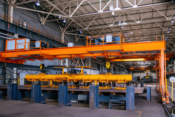 Overhead crane with magnetic grippers lifting steel sheets