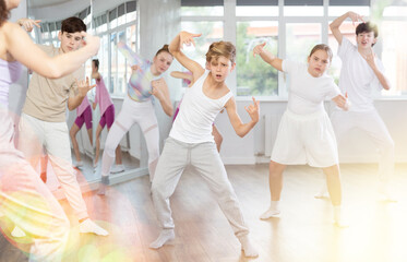 Naklejka premium Group of boys and girls rehearsing hip hop dance in studio
