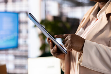 CEO evaluating company performance with tablet by analyzing and interpreting data metrics. Close up of manager using device, ensuring compliance with legal, regulatory and safety standards
