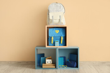 School bags and stationery in boxes near beige wall in room