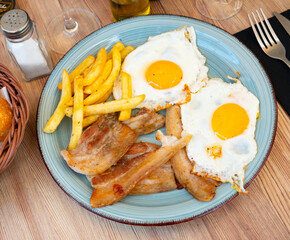 Delicious breakfast - scrambled eggs with bacon and french fries