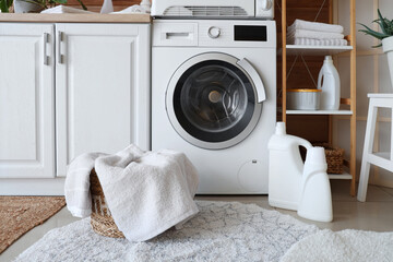 Interior of home laundry room with modern washing machine, counter, shelving unit, dryer and basket...