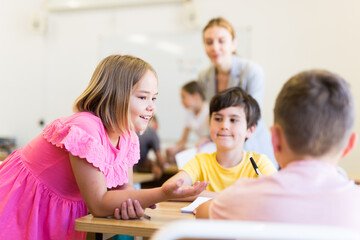 Small school kids, girls and boys, sitting together and discussion project in groups at lesson in school