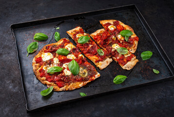 Traditional Italian pinsa bread prosciutto e salsa di pomodoro with Parma ham, buffalo mozzarella tomato sauce served as close-up on an old rustic tray