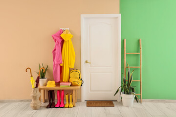 Interior of hallway with raincoats, bench and door