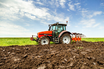 Obraz premium Tractor cultivating fertile soil on a sunny day, preparing the land for the upcoming planting season