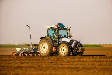 Tractor with a plow attachment tilling the soil in a vast farmland setting