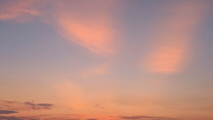A soft, pastel sunrise fills the sky with delicate shades of pink and orange. Wispy clouds create a...