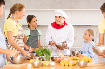 Cooking class, culinary, food and people concept - happy group of children and male chef cook cooking in kitchen