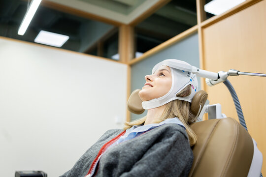 A Caucasian girl between 20 and 30 years old undergoes transcranial magnetic stimulation therapy at a psychiatric center to treat depression or anxiety.EMT concept.