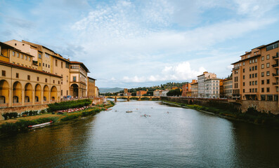 Obraz premium Athletes are rowing on the arno river in florence, italy, with the ponte vecchio and the uffizi gallery in the background, creating a picturesque scene of sport and history