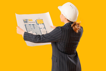 Young female architect with blueprint on yellow background, back view. Woman in male profession...