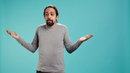 Naklejka premium Man shrugging shoulders, unable to provide answer, having detached apathy facial expression. Apathetic person doing hand gesturing showing lack of knowledge, studio background, camera B