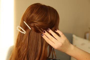 Teenage girl with stylish hair clips indoors, back view