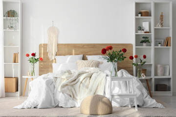 Vases with beautiful dahlia flowers on bedside tables in light bedroom
