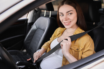 Smiling pregnant woman fastening safety belt in car, view from outside
