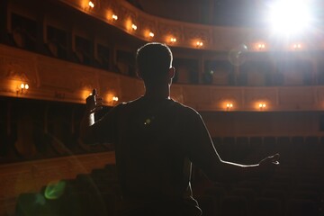 Professional actor rehearsing on stage in theatre, back view