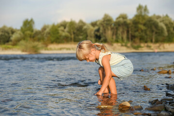 Fototapeta premium Cute little girl spending time on river. Child enjoying beautiful nature
