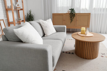 Interior of living room with grey sofa, table and drawers