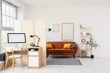 Interior of stylish living room with brown sofa, folding screen and comfortable workplace