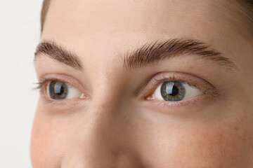 Young woman with beautiful eyes on light background, closeup