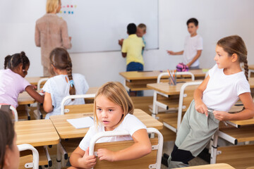 Positive primary school students are talking about homework at the desk