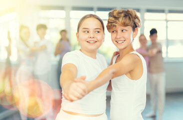 Group of positive teenagers learning to dance tango in a dance studio