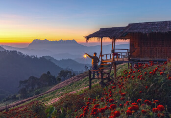 Travel male holding storm lantern enjoying Mountain peaks in morning fog - foggy morning Landscape of sunrise on Mountain at Doi Luang Chiang Dao, Chiang Mai ,Thailand